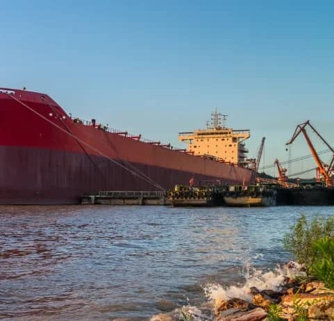 Bulk carrier ship moored at a river port with a crane alongside